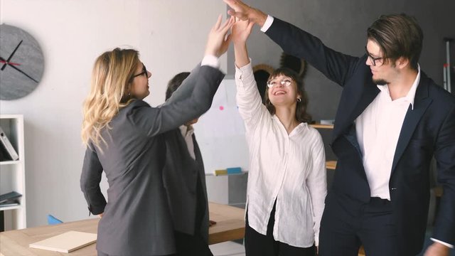 Cheerful young group of people discuss something in the office and giving high five