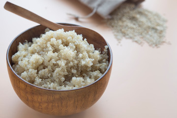  cooked quinoa in bowl and wooden spoon on brown background