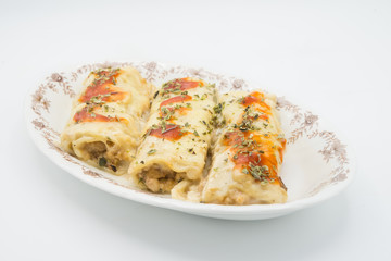 Canelones (cannelloni) with meat filled pasta and cheese and tomato on a plate