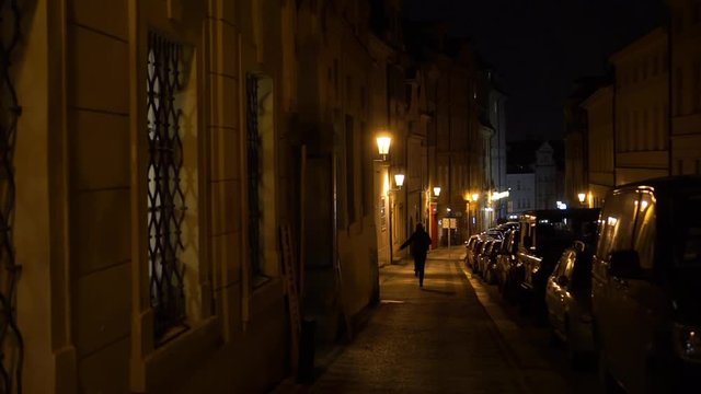 Woman run dancing on dark European old town street