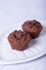 Chocolate muffins on a white plate. Homemade baking. White background. Selective focus, close up.