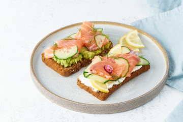 Smorrebrod - traditional Danish sandwiches. Black rye bread with salmon, cream cheese, cucumber, avocado on wooden background