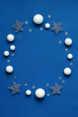 Ornate Christmas decorations frame on classic blue color background. Silver, golden and red ornaments flat lay, background for Christmas, New Year, copy space