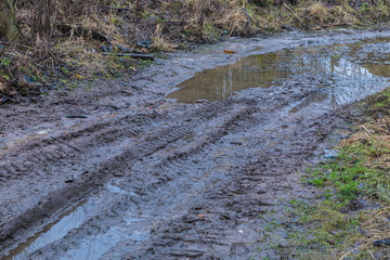 The bad ground or soil rural or suburb road or way with puddles, pools, mud and slush