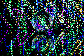 brilliant view of long exposure light painting experiment with lens ball placed over glass for reflection using a tripod inside a complete dark room for Christmas festival celebration