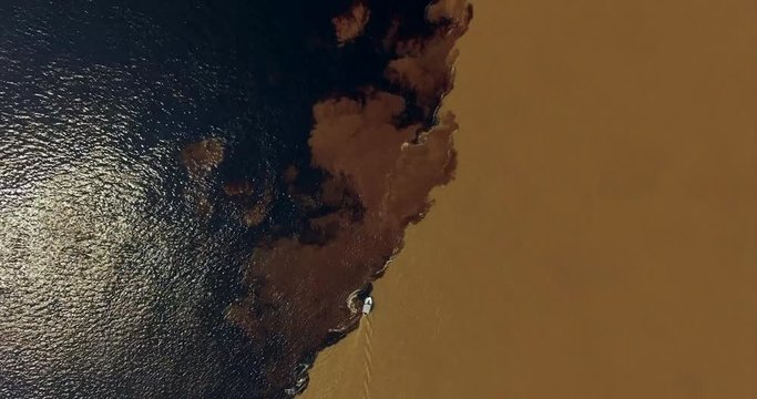 A popular tourist destination in Brazil. At this point, the black waters of the Rio Negro merge with the sandy-colored waters of the Solimines River. Manaus. Aerial view, 4K