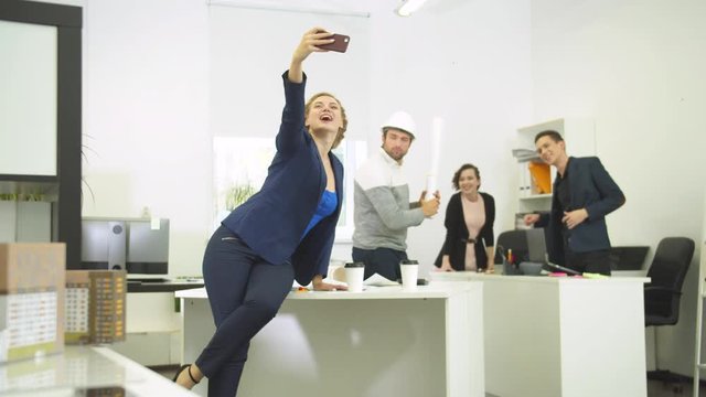 Slow motion, woman makes photos with her workmates during working day 
