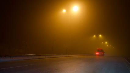 road lighting poles and car headlight on a foggy night