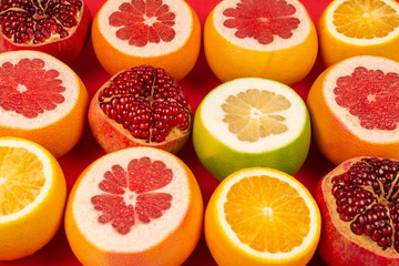Grapefruit, orange, pomegranate, citrus sweetie on red background.