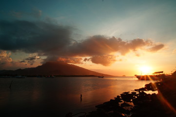 Sunset and sunrise are the natural beauty at the end of the night and at dusk giving the perfect color to the sky so the clouds look beautiful to be seen with the beach set against a mountain.