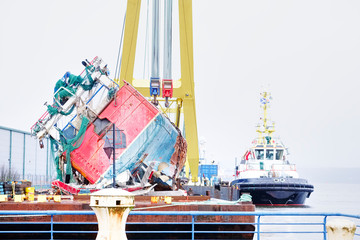 Fototapeta na wymiar Capsized ship vessel and rescue lift crane at port dock for repair of shipwreck
