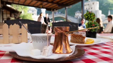 Traditional Bosnian coffee on the table with the view of Mostar Old bridge in the background, Bosnia and Herzegovina.  Traditional turkish coffee and turkish delight. 