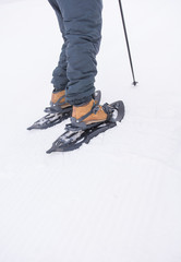 A sporty man putting on his snowshoes to start a snowy mountain excursion.