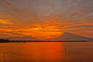 Sunset and sunrise are the natural beauty at the end of the night and at dusk giving the perfect color to the sky so the clouds look beautiful to be seen with the beach set against a mountain.