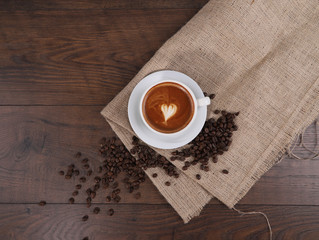 Cup of coffee, coffee bean with tablecloth on the wood table