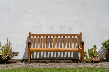 Wooden bench front of a white wall