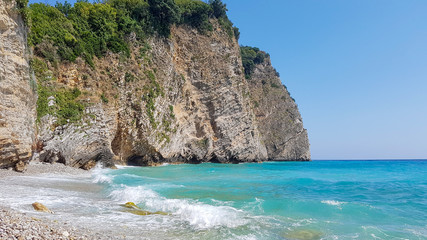 Obraz premium Panoramic view of pebble beach with clear azure blue water and layered rocks, beautiful mediterranean Adriatic Sea coast, Montenegro, selective focus