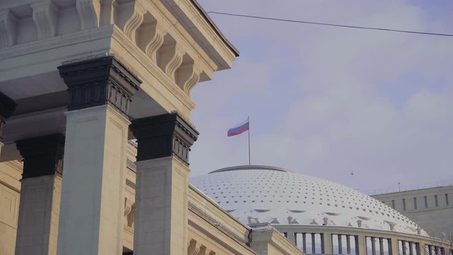 Novosibirsk, Novosibirsk Region, Russian Federation, 23/12/2019. Novosibirsk Opera and Ballet Theatre on Lenin square. Snow-covered dome of the theater, and the flag of Russia, close-up.
