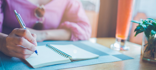 Woman hand taking notes on a notebook using a pen.