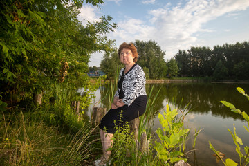 Fototapeta na wymiar Russian lady sits on the background of the lake