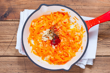 Step-by-step cooking of fried carrots with onions in a pan, step 4 - adding spices and tomato...