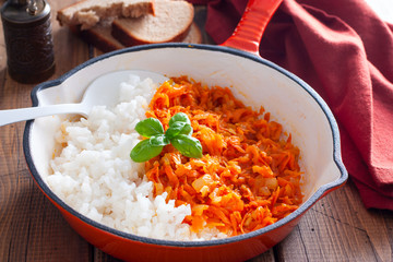 Fried carrots with onions in a pan with boiled rice, selective focus