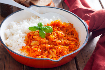 Fried carrots with onions in a pan with boiled rice, selective focus