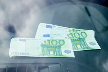 Euro banknotes on the dashboard and their reflection in the windshield inside of a car