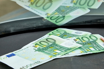 Euro banknotes on the dashboard and their reflection in the windshield inside of a car