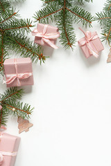 Christmas flat lay. Holiday gifts in boxes in pink packaging and fir branches on a white background with copy space, top view.