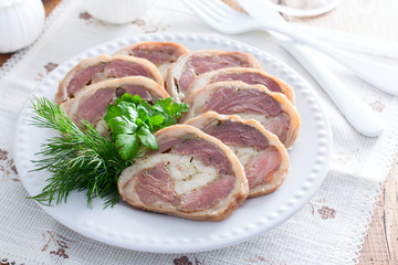 Cooked pork knuckle roll with chicken on a white plate, horizontal