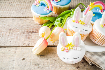 Easter holiday greeting card background. Cute homemade cupcakes with traditional Easter bunny, egg and springtime flowers decor. Happy easter concept. Copy space for your text