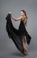beauty fashion portrait of young slim girls. The model stands with his back holding the edge of her dress
