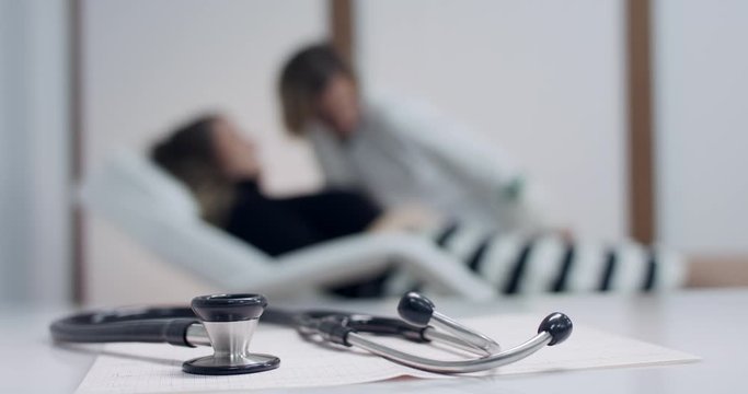 Closeup of stethoscope on the electrocardiogram (EKG). Doctor and Patient blurred background. Tracking shot