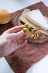 hand holds olive on a background of cheese and nuts