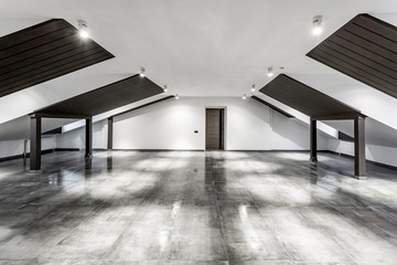 Empty unfurnished loft mansard room interior with wooden columns and wet concrete floor on roof level in black and whote style color