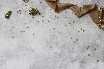 New Year festive composition, web banner with black and gold confetti stars and silk ribbbon. Party decoration, celebration concept. Flat lay, top view. Grunge concrete background. Empty copy space.
