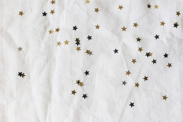 Christmas, New Year composition. Decorative golden and black confetti stars on white linen...