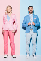 smiling woman and handsome man looking at camera on pink and blue background