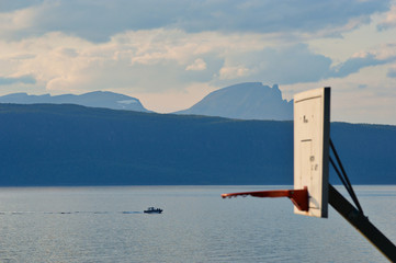 Basketball hoop in front of big mountains and fjord on Ornesvik beach in Narvik, Norway
