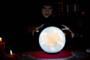 Blur image of Beautiful young Asian woman Gypsy Fortune teller glowing crystal ball, tarot cards...