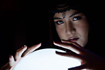 Beautiful young Asian woman Gypsy Fortune teller glowing crystal ball, tarot cards and composition of esoteric astrology object to predict destiny or future. - obrazy, fototapety, plakaty
