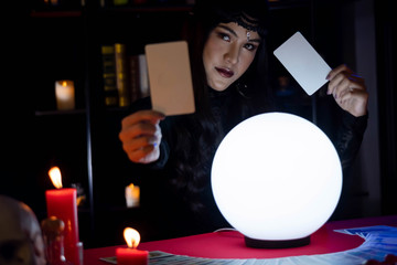 Beautiful young Asian woman Gypsy Fortune teller glowing crystal ball, tarot cards and composition...