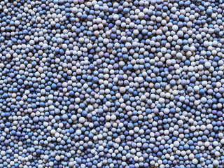 A lot of tiny ceramic balls or granules in color range from beige to dark blue as a background....