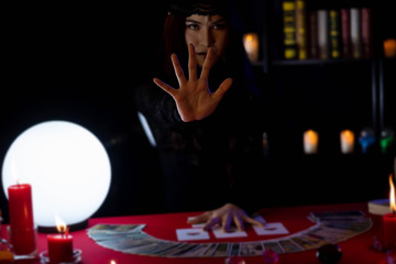 Hands of Beautiful young Asian woman Gypsy Fortune teller glowing crystal ball, tarot cards and...
