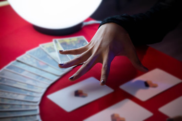 Hands of Beautiful young Asian woman Gypsy Fortune teller glowing crystal ball, tarot cards and...
