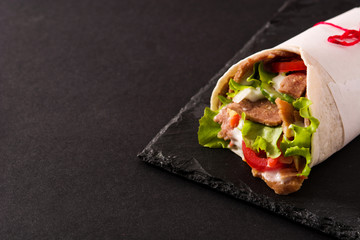 Doner kebab or shawarma sandwich on black slate background.Copy space
