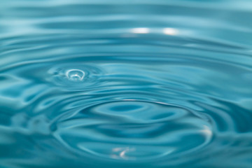 Closeup Water drop falling on the surface of the water and beautiful circular wave ripple, fresh natural mineral water drink water concept