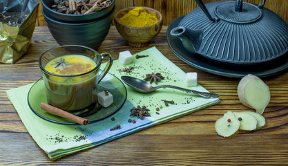 Masala tea. A Cup of traditional Indian tea masala tea with ingredients to prepare. Cinnamon, anise, sugar, black tea, pepper, cloves, turmeric on a wooden table.