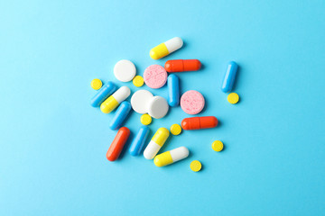 Many pills on blue background, top view and space for text